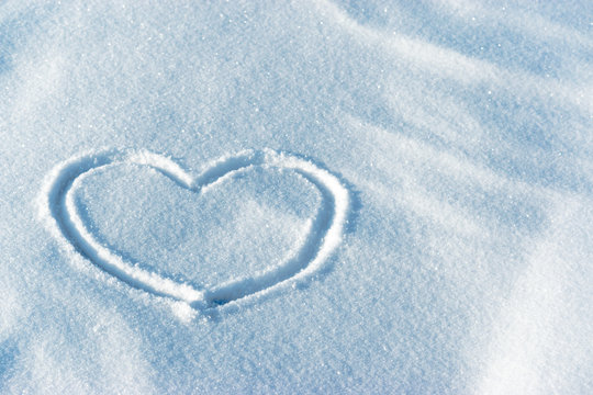 Shape of a heart in the light blue bright snow. Leftside view. Valentine's day pattern. Symbol of love