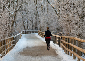 Joggerin von hinten im Winter in einem verschneiten Wald 