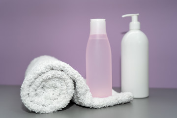 Obraz na płótnie Canvas Cosmetic bottles with shampoo and towel in pink and white colors