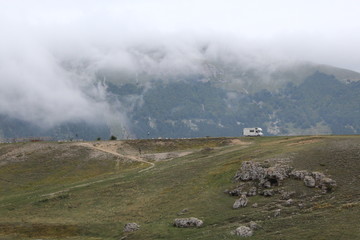 Camper driving on a mountain road with low clouds