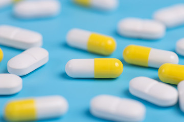 Yellow and white pills or capsules on a blue background