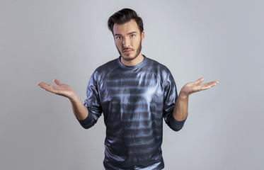 I don't know concept. Portrait of a young man who do not understand what is happening. Man in white turtleneck raises hands and shrugging his shoulders on a gray background copy space