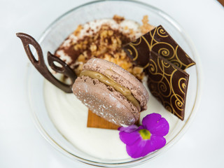 fresh chocolate mousse in a transparent cup, decorated with chocolate macaroons, thin slices of chocolate and a beautiful little blue flowers