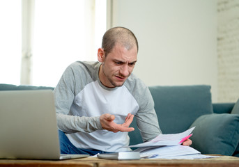 Fototapeta premium Upset man in stress paying credit card online debts and counting finance with laptop and bank papers