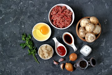 Ingredients for cooking meatloaf: minced meat, mushrooms, egg, white bread, onion, garlic, tomato paste, soy sauce, salt, pepper.