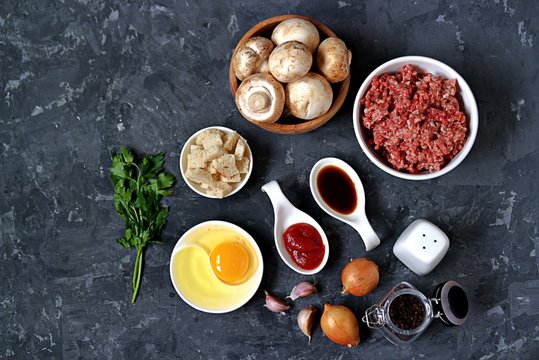 Ingredients for cooking meatloaf: minced meat, mushrooms, egg, white bread, onion, garlic, tomato paste, soy sauce, salt, pepper.
