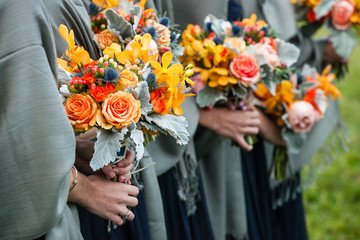 bridesmaids holding their wedding bouquets of flowers with yellow, red, blue and orange flowers
