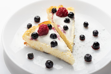 Cheesecake with cream and fresh raspberries and blueberries.