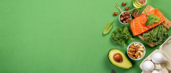 Keto-dieetconcept - zalm, avocado, eieren, noten en zaden, heldergroene achtergrond, bovenaanzicht