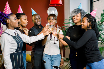 Portrait of happy young African friends touching the glasses with each other and celebrating birthday
