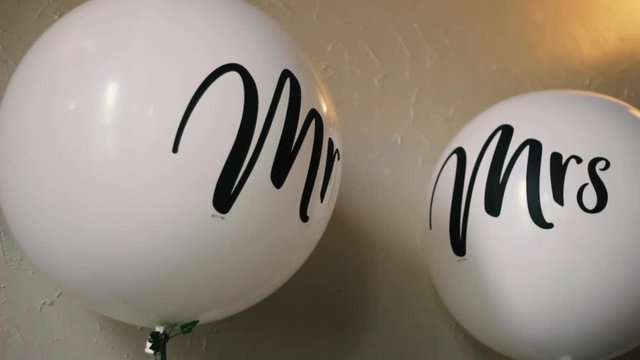 A close up of a set of Mr & Mrs balloons hovering and subtly moving before the newly married couple join the wedding party to resume their special day