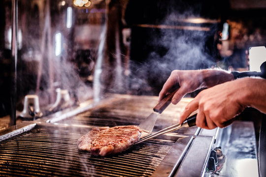 Close-up image of a cooking delicious meat steak on a grill in a restaurant kitchen.