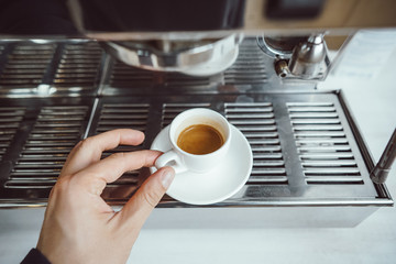 close-up view of glass cup with cappuccino and coffee machine