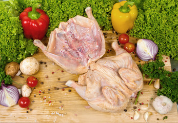 Two chickens are stacked in a row on a wooden cutting machine