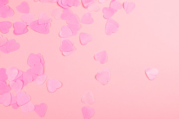 Pink background with heart-shaped confetti.