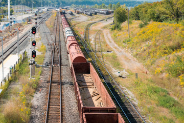 Fototapeta na wymiar Birds-eye view of freight train - cargo leaving moving through rail yard with network of stored trains