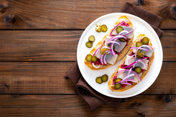 Delicious grilled sandwiches with herring, onion and beetroot sauce with horseradish on dark wooden rustic background. Danish cuisine. Top view