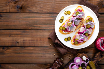 Delicious grilled sandwiches with herring, onion and beetroot sauce with horseradish on dark wooden rustic background. Danish cuisine. Top view