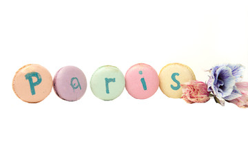 colorful macaroons, almond cookies, with the help of macaroons lined the word Paris, decorated with fresh flowers