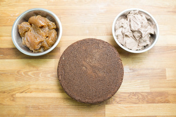 Chocolate cakes for a Prague cake on a wooden board, ingredients for the filling: cream and apple jam