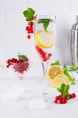 Detox infused flavored water of lemon red currant, and mint. Refreshing summer cocktail in glass for champagne .Summertime.