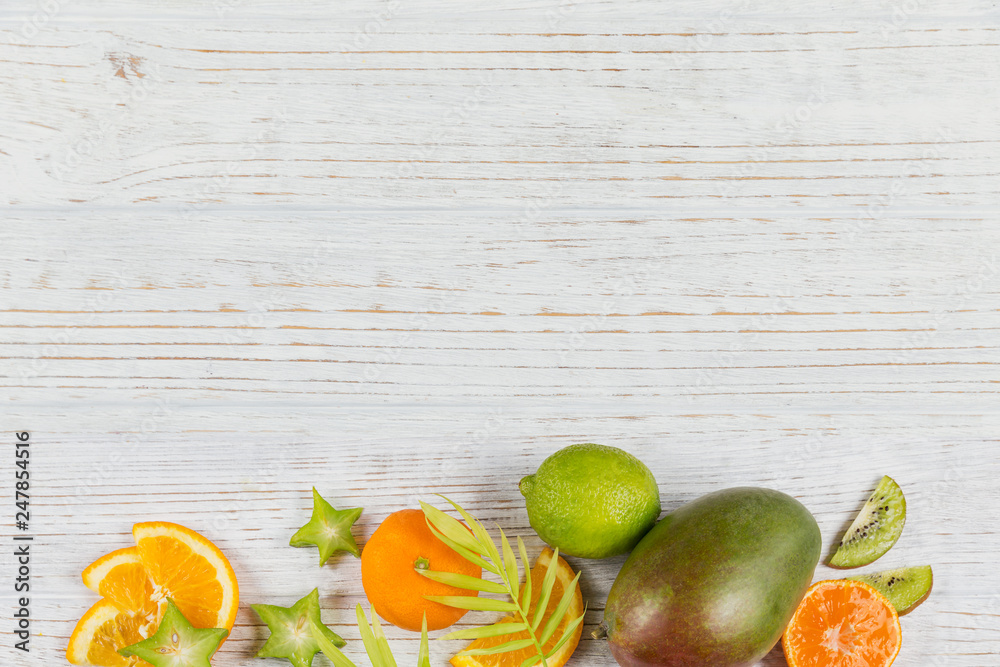 Wall mural Green palm leaves and fresh tropical slices of fruits