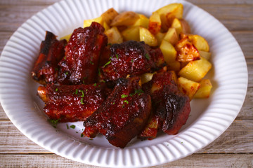 Grilled pork spare ribs with fries on white plate. Roasted sliced barbecue ribs. horizontal