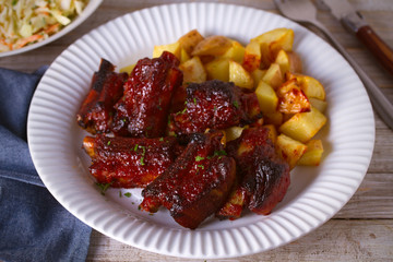 Grilled pork spare ribs with fries on white plate. Roasted sliced barbecue ribs. horizontal