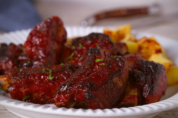 Grilled pork spare ribs with fries on white plate. Roasted sliced barbecue ribs. horizontal