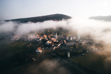 Eine Stadt mit Häusern und Kirche im Nebel aus der Luft 