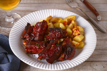 Grilled pork spare ribs with fries on white plate. Roasted sliced barbecue ribs. horizontal