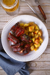 Grilled pork spare ribs with fries on white plate. Roasted sliced barbecue ribs. overhead, vertical
