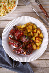 Grilled pork spare ribs with fries on white plate. Roasted sliced barbecue ribs. overhead, vertical