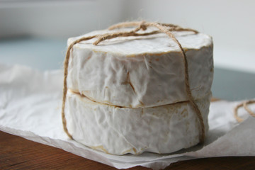 Camembert cheese close-up. Round Camembert cheese on the white paper, the background of the tree. Gourmet cheese, cheese plate, wine food. Camembert cheese. Fresh brie cheese and cut on a wooden Board