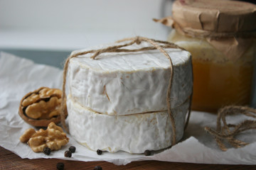 Camembert cheese close-up. Round Camembert cheese on the white paper, the background of the tree. Exquisite cheese, cheese plate, wine food. Camembert cheese. Fresh brie cheese and sliced on a wooden 