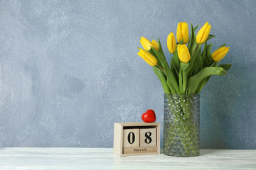 Beautiful yellow tulips in a glass vase on white background for Mother's Day. Space for text