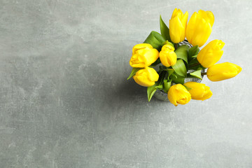 Beautiful bouquet tulips in vase on gray background, top view. Space for text