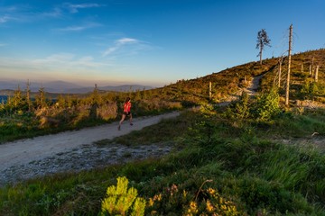Young woman cross running in mountains at summer