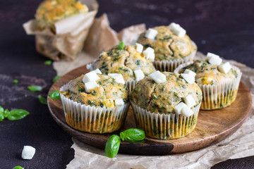 Savory muffins with spinach and feta cheese on old brown concrete background.