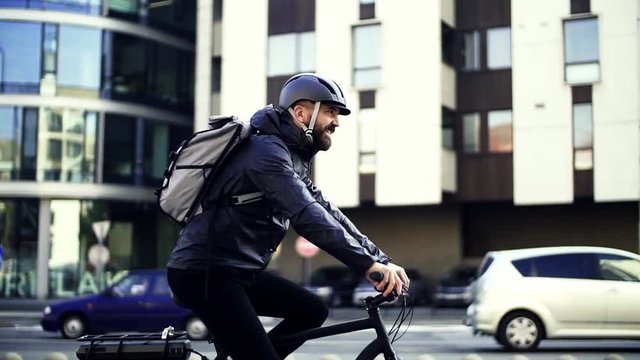 Male courier with bicycle delivering packages in city. Slow motion.