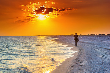 Tourist hike along the sea surf in the rays of the summer sun at sunset