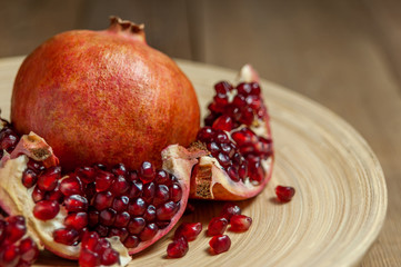 open pomegranate and flat plate on wooden table