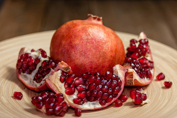 open pomegranate and flat plate on wooden table