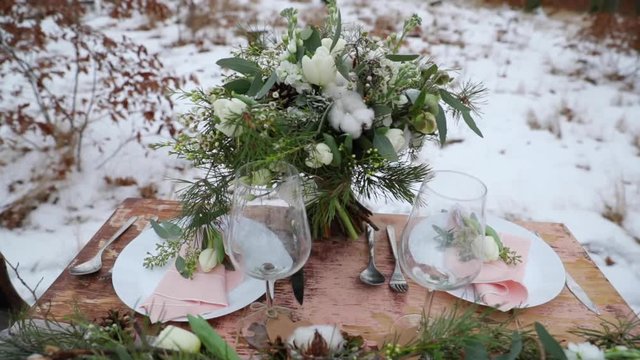 Winter wedding bouquet on table in the middle of forest on snow decoration old wooden table on it decoration of coniferous trees