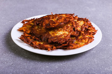 Hash brown and sour cream on a plate against a gray stone background, well fried. Copy space.