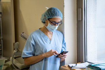 Female surgeon doctor consults the mobile phone before operation.