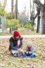 A woman and a child playing with an autumn fall leaf