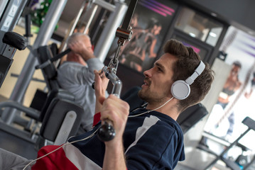 Fototapeta na wymiar Young sporty man listening music while exercising in the gym