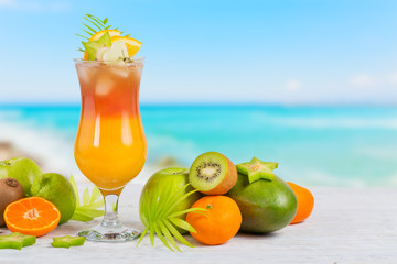 Summer cocktail with various tropical fruits around. Apple, kiwi, tangerine, orange, mango,...