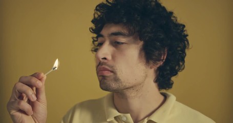 Man against yellow background blowing match